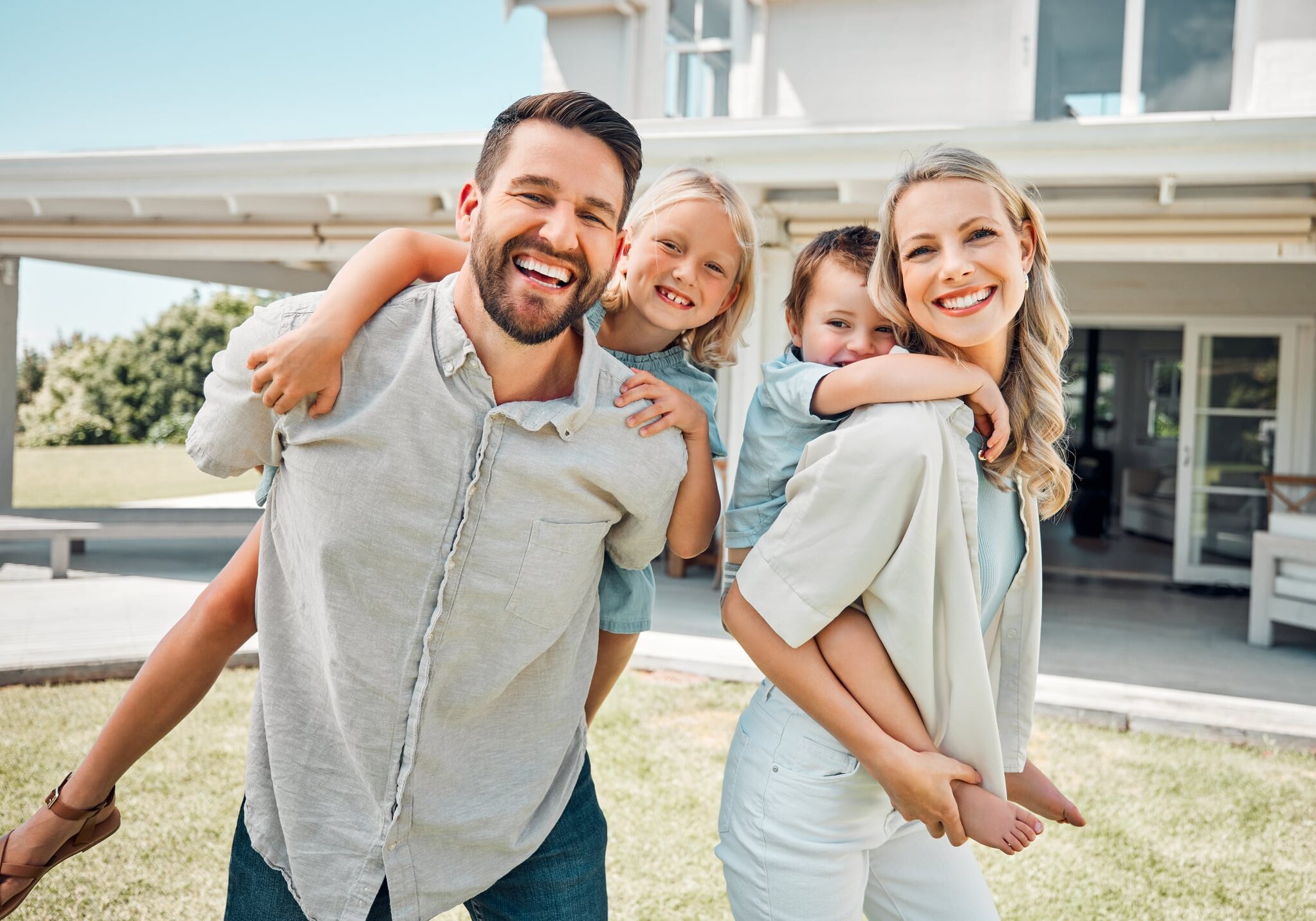 Portrait of a happy carefree caucasian family bonding and relaxing together in the garden or backyard at home. Loving parents carrying their smiling playful son and daughter to enjoy piggyback rides